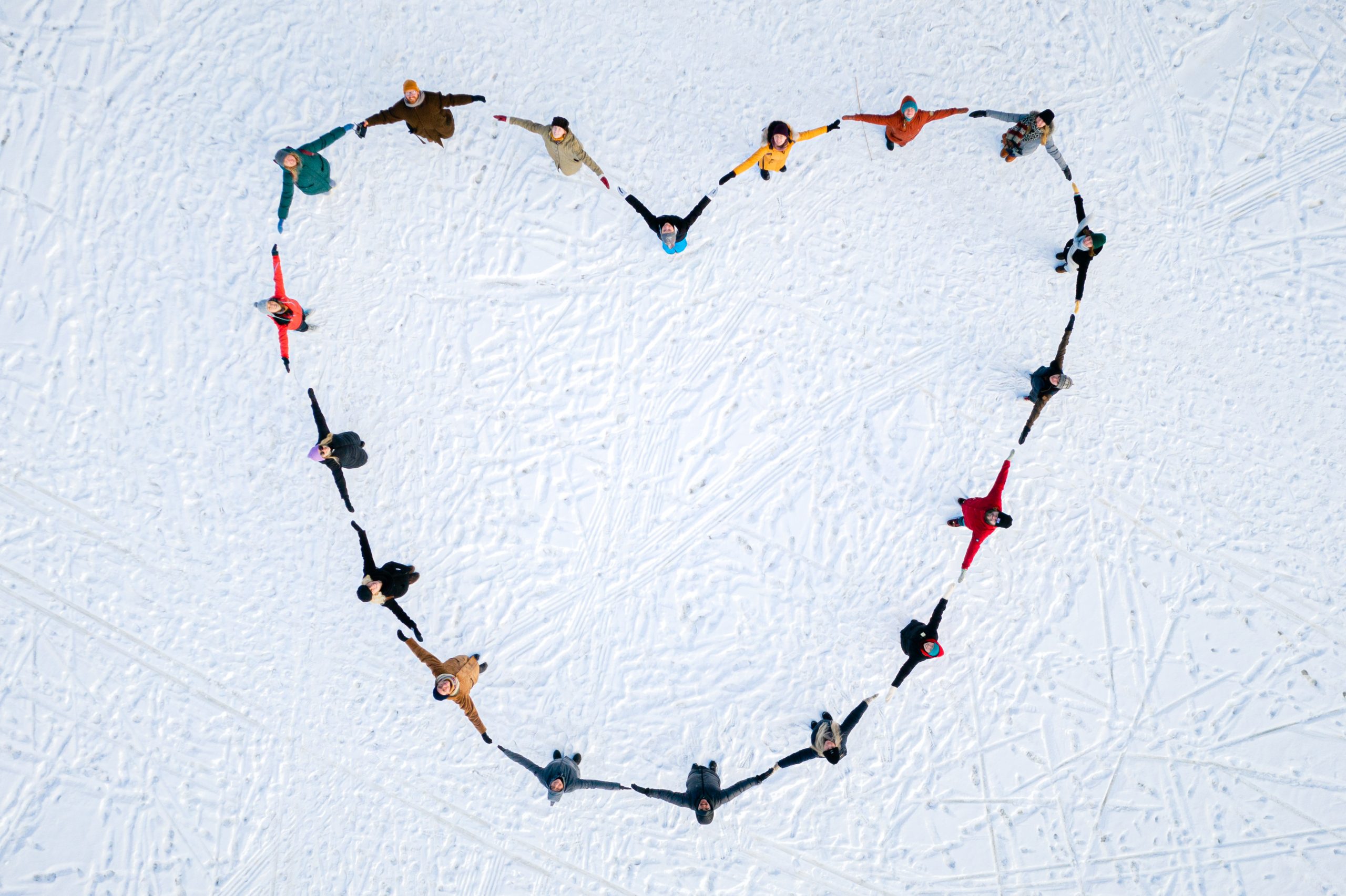 Colourful people making a heart on ice, drone photo from above